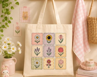 May include: A cream-colored canvas tote bag featuring a grid of nine square patches, each displaying a different colorful flower illustration. The flowers include daisies, sunflowers, and tulips in various pastel shades, arranged in a three-by-three pattern.