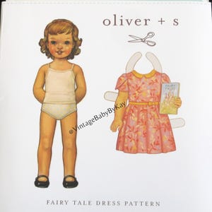 May include: A vintage paper doll dress pattern by Oliver + S. The cover features a paper doll with a tank top and underwear, and a dress with a floral pattern. The text "FAIRY TALE DRESS PATTERN" is at the bottom.