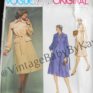 May include: A Vogue Paris Original sewing pattern envelope for a Pierre Balmain coat, numbered 1498. The white paper envelope features illustrations of a beige belted coat and a purple coat, with the text Vogue Paris Original and 1498 Pattern/Patron.