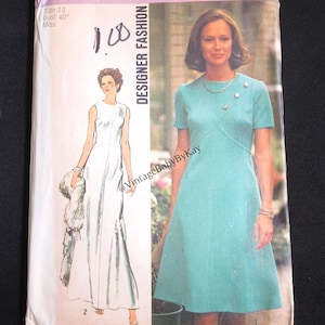 May include: Vintage Simplicity Designer Fashion sewing pattern. The pattern features a teal dress with short sleeves and a cross-over design, and a white gown. The pattern size is 18, with a 40-inch bust. The price is $1.25 in Canada.