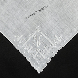 May include: White linen handkerchief with embroidered details and a decorative border. The handkerchief features the letter "V" in the center of the design. The text "@VintageBabyByKay" is visible in the image.