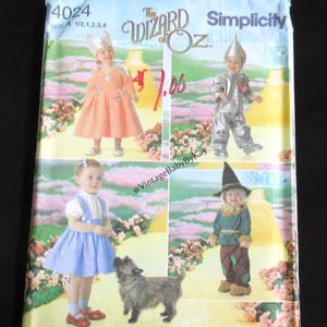 May include: A Simplicity sewing pattern envelope for The Wizard of Oz costumes, numbered 4024, featuring illustrations of children in character outfits including a dress, a tin person suit, and a scarecrow costume, with a small dog depicted.
