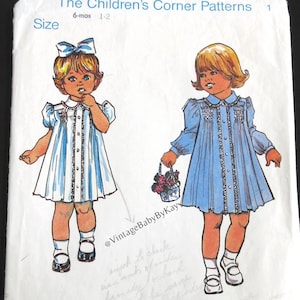 May include: Vintage sewing pattern titled "The Children's Corner Patterns" featuring illustrations of two little girls in dresses. The pattern is for sizes 6 months to 1-2 years old. The design is by Elizabeth Travis Johnson.
