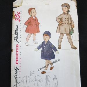 May include: A vintage Simplicity printed pattern envelope featuring illustrations of children wearing double-breasted coats and hats. The cover displays three distinct outfits in red, blue, and plaid, along with line drawings of the garment construction.