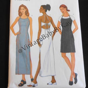 May include: A Butterick sewing pattern envelope, number 6526, featuring illustrations of three different dress styles. The white envelope displays a blue long dress, a white backless halter dress, and a dark gray knee-length dress with a white t-shirt.