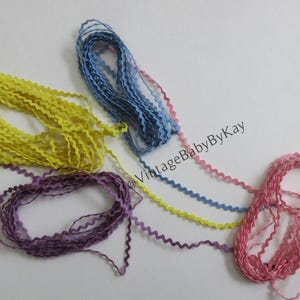 May include: A collection of colorful, wavy ribbons in shades of yellow, purple, blue, pink, and a mix of colors. The ribbons are arranged on a white surface. The ribbons have a zig-zag edge.