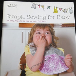 May include: A book titled "Simple Sewing for Baby" with a photo of a baby wearing a bib. The book cover features the author's name, Lotta Jansdotter, and the subtitle "24 Easy Projects for Newborns to Toddlers."