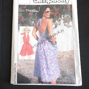 May include: A vintage Simplicity sewing pattern envelope featuring a halter dress design. The envelope has the number 6888 and the name Ali MacGraw. The dress illustration is a purple and blue floral print.