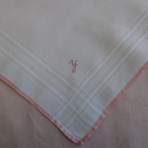 May include: White handkerchief with a pink embroidered border and the initial "Y" in pink thread.