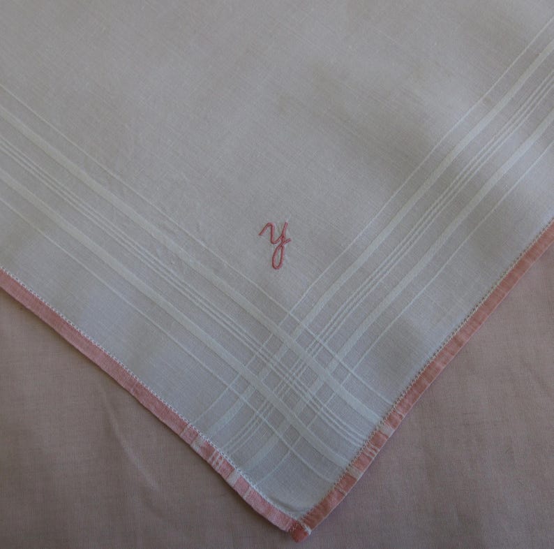 May include: White handkerchief with a pink embroidered border and the initial "Y" in pink thread.