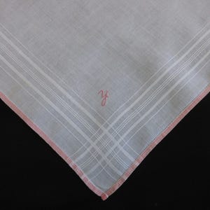 May include: White linen handkerchief with a pink embroidered border and the initials "Y.F." in pink.
