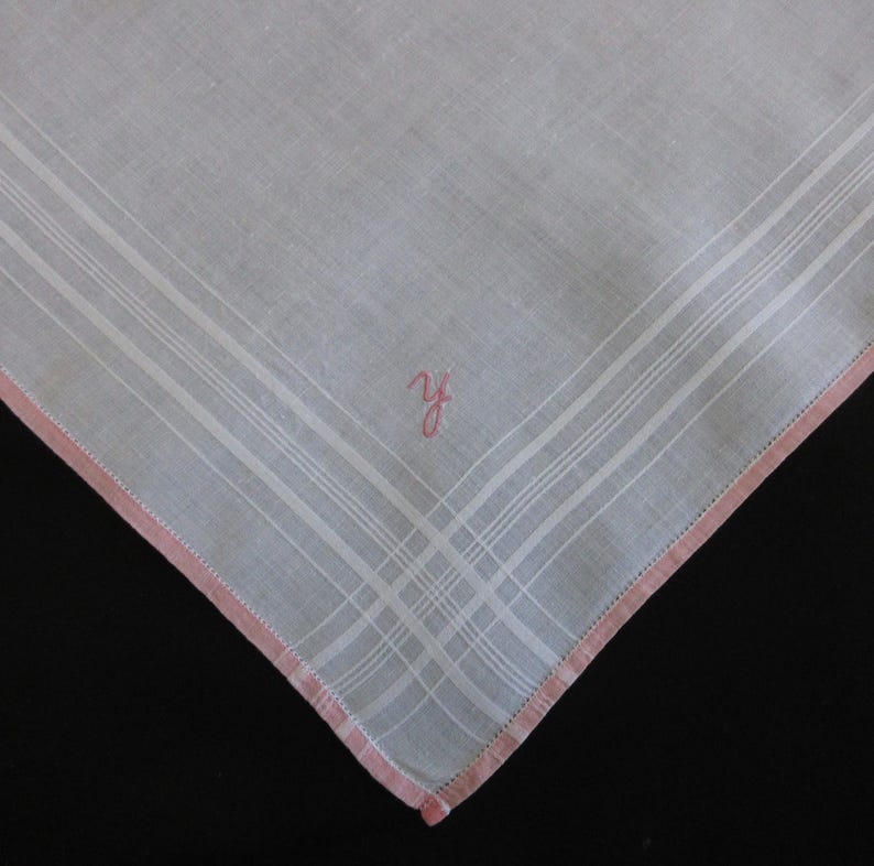 May include: White linen handkerchief with a pink embroidered border and the initials "Y.F." in pink.