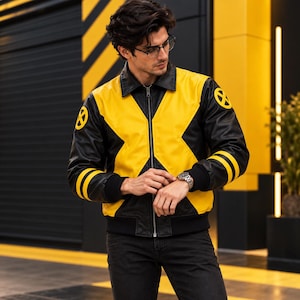 May include: A black and yellow leather jacket featuring a prominent X-shaped design on the front, a classic collar, a full-length front zipper, and circular yellow and black X-Men logos on each shoulder, with two yellow stripes on the sleeves.