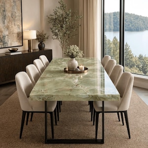 May include: A rectangular dining table with a polished light green onyx stone top featuring natural veining and a black metal frame. The table is surrounded by eight upholstered chairs in a neutral beige fabric with dark wooden legs.