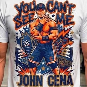 May include: A white t-shirt featuring a graphic print of John Cena in a wrestling ring. The text "YOU CAN'T SEE ME" appears above the figure, and "JOHN CENA" is printed below. The design includes blue, orange, and white colors with stars.