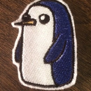 May include: White and blue embroidered penguin patch with a black outline. The penguin has a small, black beak and a black eye.