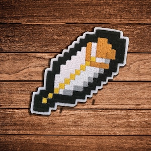 May include: An embroidered patch shaped like a pixelated feather. The design features a black border, a white center, and a yellow and brown accent section near the top. The embroidery has a distinct blocky, digital aesthetic with a white outline.