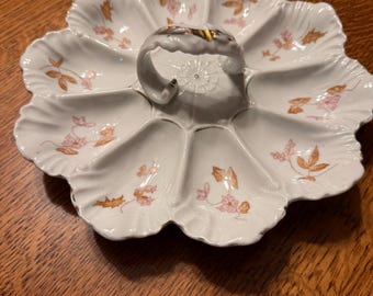 Plato antiguo de porcelana AK Limoges de 9 cavidades para ostras con asa central y detalles florales dorados.