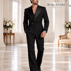 May include: A black tuxedo suit featuring a cropped double-breasted jacket with satin peak lapels and a single button closure, paired with matching high-waisted pleated trousers. The text Ruby Attire Wear Your Story is visible in the upper right.