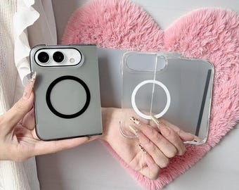 Może przedstawiać: Dwa składane etui na telefon, jedno w matowym szarym wykończeniu z czarnym okrągłym pierścieniem magnetycznym, a drugie w przezroczystym wykończeniu z białym okrągłym pierścieniem magnetycznym, oba z prostokątnym wycięciem na aparat u góry.