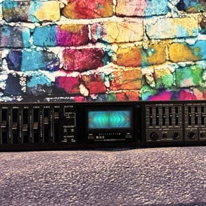 May include: A black Sansui RG-710 stereo graphic equalizer console featuring multiple vertical sliders, a central illuminated display screen with a blue and green light pattern, and various control knobs and switches on the front panel.