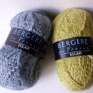 May include: Two skeins of yarn, one blue with silver glitter and one green with white glitter. Both skeins have a label that reads "Bergere de France Eclair".