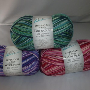May include: Three skeins of yarn in different color combinations. Each skein is labeled "Supersocke 4-fach Nature Color 100 Gramm ca. 420 Meter". The colors are green, purple, and pink.
