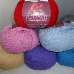 May include: A collection of Ella Rae Superwash Classic Wool yarn skeins in red, pink, light blue, tan, purple, and dark blue. The red skein features a label with the text Ella Rae Superwash Classic Wool, machine-washable pure virgin wool, 3.52 oz, 219 yds.