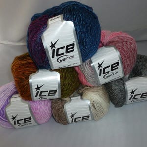 May include: A collection of colorful yarn skeins, each with a label from "ice yarns". The skeins display a variety of colors, including blue, pink, brown, green, and gray. The yarn is arranged in a pile, showcasing the different hues and textures.