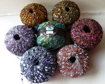 May include: Six balls of yarn in various colors, including green, purple, orange, and red. Each ball has a silver metallic thread woven throughout. The yarn is labeled "Beautiful Dark Horse Yarns".
