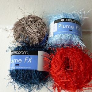 May include: Four skeins of yarn in different colors: brown, light blue, teal, and red. The yarn is fluffy and has a fuzzy texture. The yarn labels read "Berroco Plume FX" and "Just in Fashion: www.berroco.com".