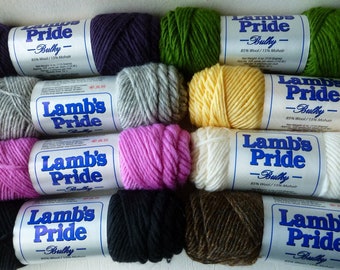 May include: A collection of ten skeins of Lamb's Pride Bulky yarn in various colors including purple, green, gray, yellow, pink, white, black, and brown. Each skein features a white paper label with blue text stating 85% Wool and 15% Mohair.