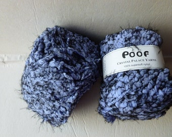 May include: Two skeins of Poof Crystal Palace Yarns in a variegated light blue and black colorway. The yarn has a textured, fuzzy appearance and is made of 100% supersoft nylon. A white paper label wraps around one skein with the brand name.