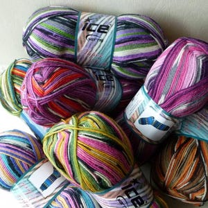 May include: A collection of colorful yarn skeins with stripes of pink, purple, green, blue, orange, and white. The yarn is labeled "Ice Yarns".