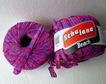 May include: Two balls of pink and purple yarn with a white label that reads "Schulana Beach".