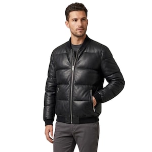 May include: A black leather bomber jacket featuring a quilted, padded design with a central silver-toned zip closure, a ribbed collar, and ribbed cuffs. The jacket includes two side pockets with silver-toned zips and a dark grey shirt underneath.