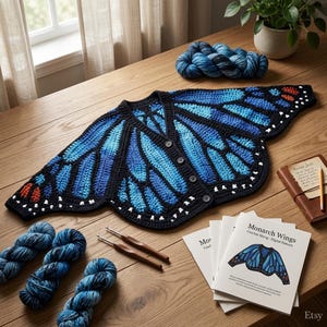 Può includere: Un cardigan all'uncinetto con un motivo ad ali di farfalla blu e nero con accenti bianchi lungo i bordi, quattro bottoni e scollo a V. Il capo è presentato con gomitoli di lana blu, due uncinetti e un libretto di istruzioni.