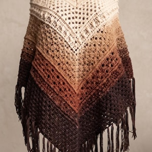 May include: A crochet poncho featuring a turtleneck collar and a V-shaped hem with fringe. The garment displays an ombre color gradient transitioning from cream at the top to dark brown at the bottom. Text reads: crochet ombre fringe poncho pattern.