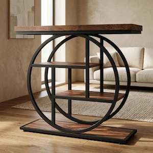 Puede incluir: Una mesa consola con tablero y base de madera veteada en color marrón oscuro y estructura de metal negro. Incluye dos estantes interiores y un gran elemento de diseño circular de metal que conecta la superficie superior con la base rectangular.