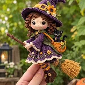 Könnte beinhalten: Eine gehäkelte Puppe als Hexe verkleidet, mit einem violetten Hut mit Sonnenblume, einem violetten Kleid mit Blumenstickerei und braunen Stiefeln. Die Puppe hält einen Besenstiel und trägt einen kleinen orangefarbenen Korb mit einer schwarzen Katzenfigur.