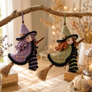 May include: Two handmade crochet witch ornaments hanging from a branch. One witch wears a purple hat and cloak with star accents, the other wears a green hat and cloak with star accents. Both have curly hair, striped legs, and ride brown broomsticks.