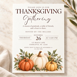 May include: A white Thanksgiving invitation card featuring brown text that reads: PLEASE JOIN US FOR THANKSGIVING Gathering, A season of gratitude, a table of friends, and a feast to share, HOSTED BY THE MILLERS, THURSDAY NOVEMBER 26 AT 4:00 PM, 123 MAPLE LANE CHARLOTTE, NC 12345, KINDLY RSVP TO EMILY BY NOVEMBER 15 123.456.7890. The bottom displays three watercolor pumpkins in orange, white, and yellow with green leaves and white berries.