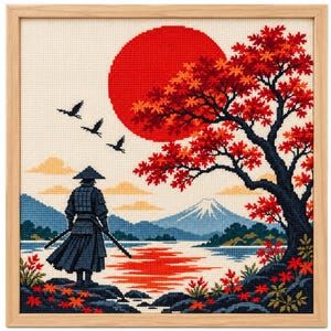 May include: A framed cross-stitch embroidery depicting a samurai standing by a lake, facing a large red sun, a vibrant red maple tree, and a distant snow-capped mountain. Three birds fly in the sky above the water, with rocky terrain in the foreground.