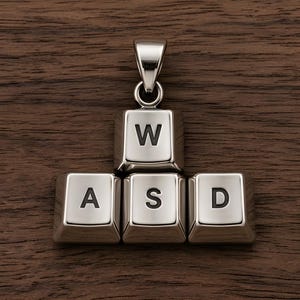 May include: A silver-toned metal pendant shaped like four computer keyboard keys arranged in a cluster. The top key is marked with the letter W, while the three bottom keys are marked with the letters A, S, and D. A metal bail is attached to the top.