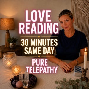 May include: A dark blue t-shirt worn by a person sitting at a table with text reading LOVE READING 30 MINUTES SAME DAY PURE TELEPATHY. The table features a deck of cards, a candle, a bowl of crystals, and a lamp in the background.