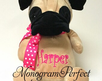 May include: A plush tan pug dog with black ears, nose, and eyes. The dog is wearing a pink ribbon with white polka dots and has the name "Harper" embroidered on its chest. The text "Monogram Perfect" is printed below the dog.