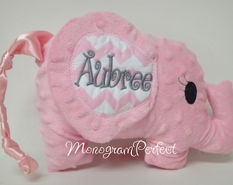 May include: Pink plush elephant with a gray embroidered name "Aubree" on a white and pink chevron fabric patch. The elephant has a pink satin tail.