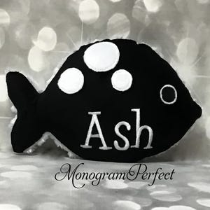 Puede incluir: Almohada con forma de pez en blanco y negro con lunares blancos y el nombre "Ash" bordado en blanco.