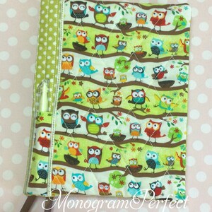 May include: A green and white quilted book cover with a pocket for a pen. The cover features a repeating pattern of owls on branches with flowers and leaves. The text "Monogram Perfect" is printed on the bottom of the cover.