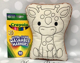 May include: A beige giraffe-shaped pillow with black outline details, next to a box of Crayola Ultra-Clean Washable Markers with 10 classic colors. The text "Monogram Perfect" is at the bottom.